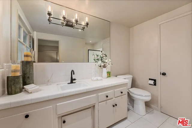 a bathroom with a granite countertop sink a toilet and a mirror