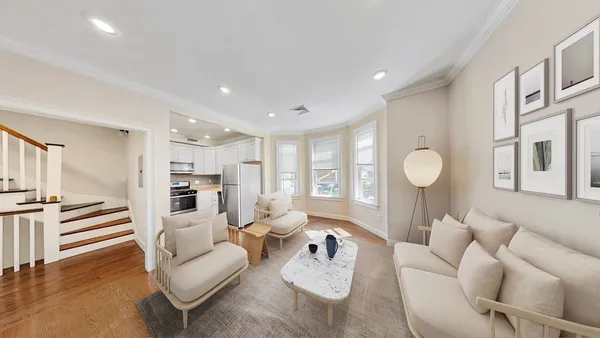 a living room with furniture kitchen view and a wooden floor