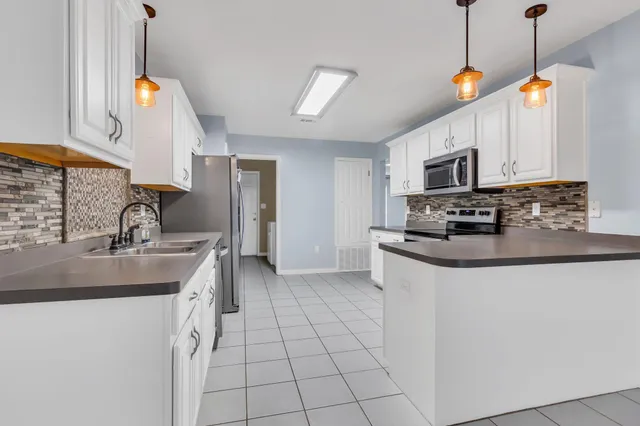 a kitchen with kitchen island granite countertop a sink a counter top space appliances and cabinets