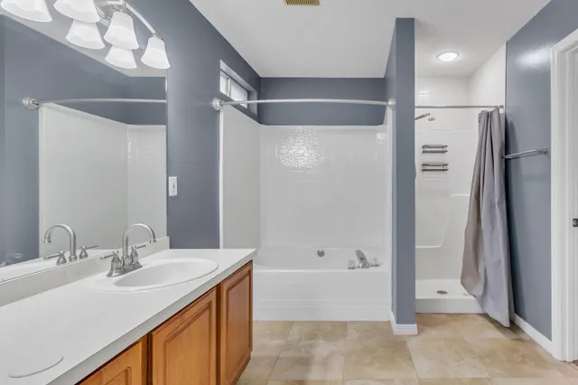 a bathroom with a granite countertop sink mirror and a bathtub