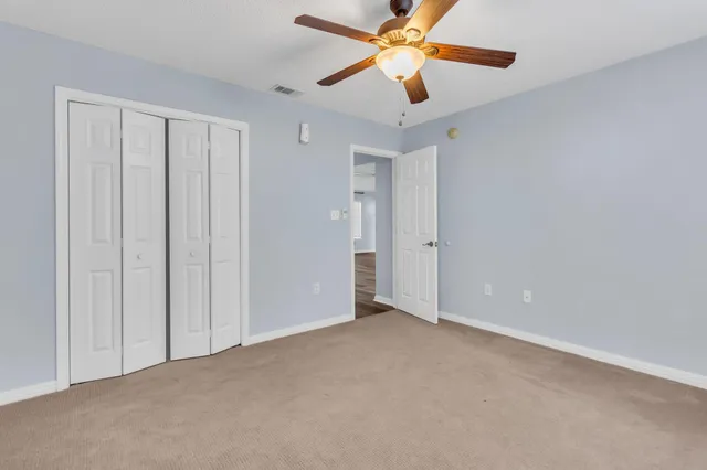 an empty room with closet and a chandelier fan