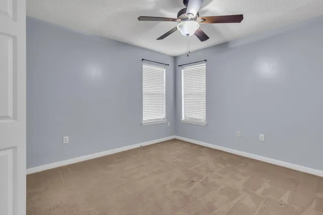 an empty room with windows and fan