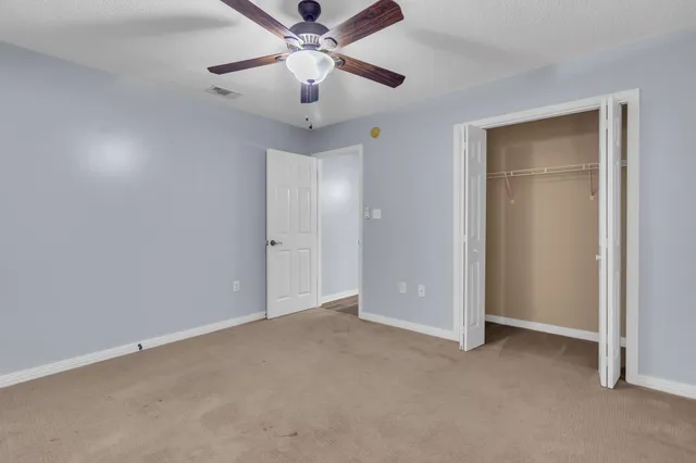 an empty room with closet and a chandelier fan