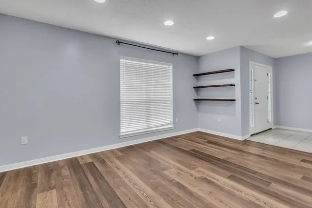 a view of empty room with wooden floor and window