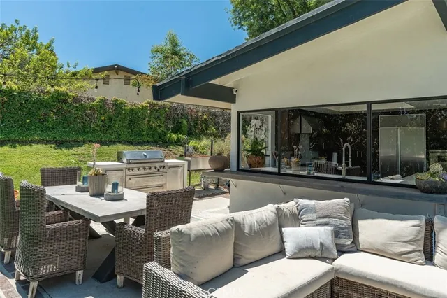 a view of a patio with couches table and chairs with potted plants and large tree