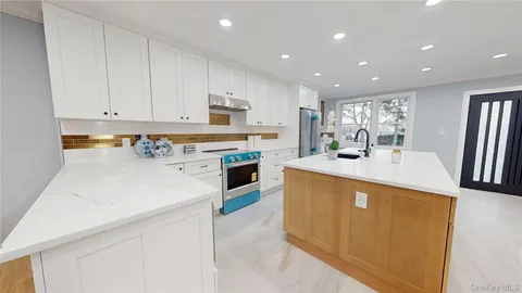 a kitchen with a sink a stove a refrigerator and white cabinets