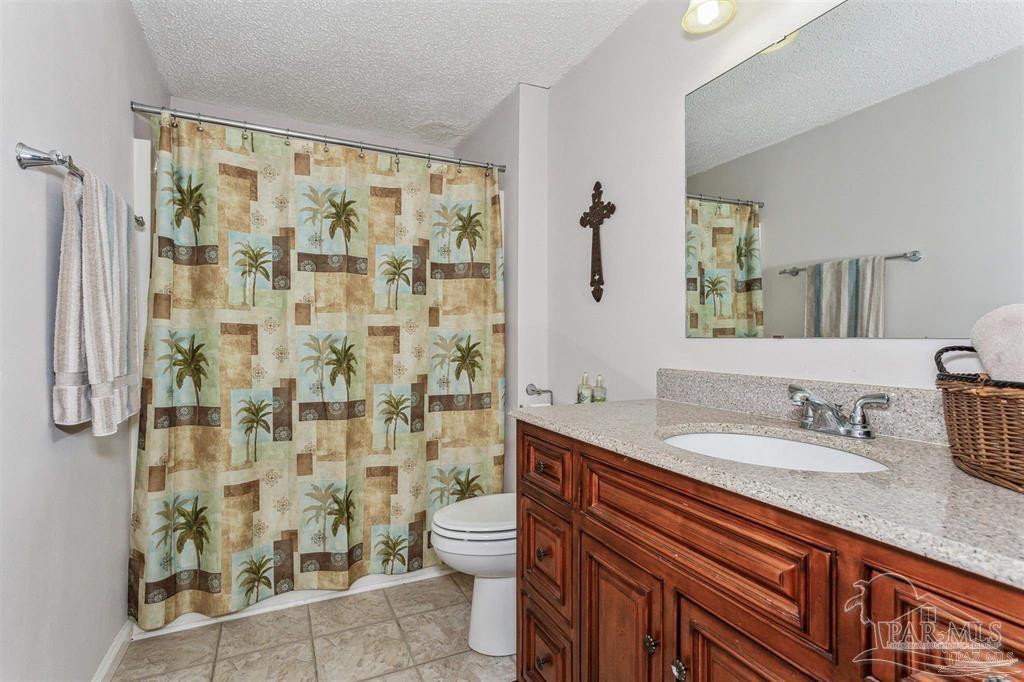 1261 Mahogany Mill Road Pensacola, FL 32507 - Photo 17 of 21 a bathroom with a granite countertop sink a toilet and shower curtain