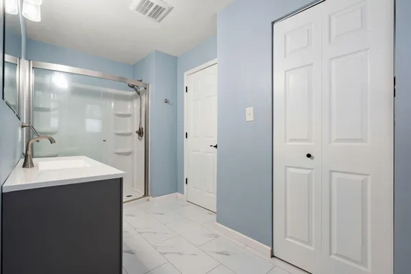 a spacious bathroom with a double vanity sink a mirror and a shower