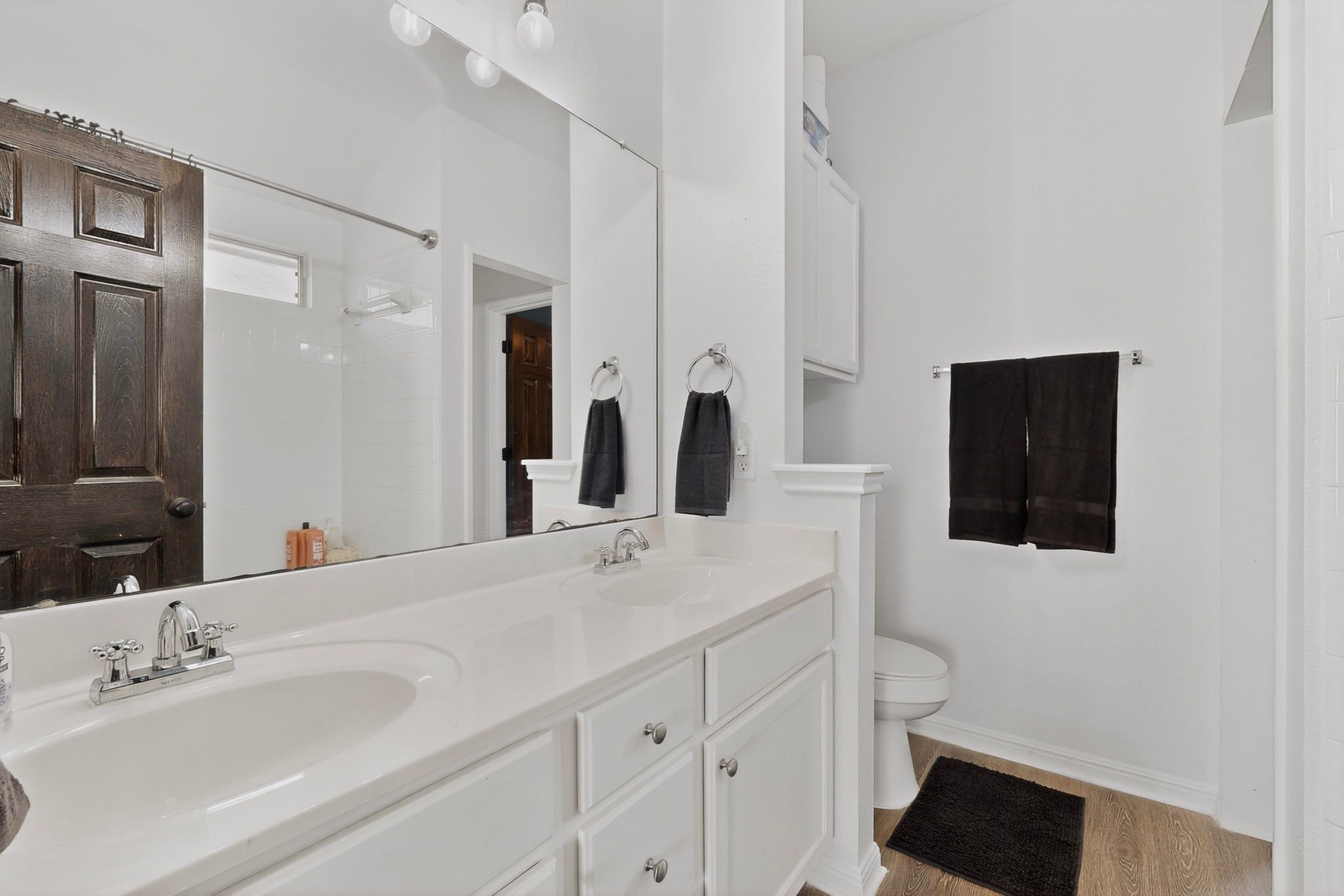 15104 Mimebark Way Austin, TX 78724 - Photo 21 of 38 Bathroom with dual vanity, white cabinetry, integrated sinks, chrome fixtures, and wood-finish flooring