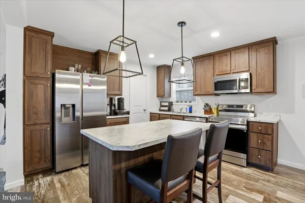 a kitchen with stainless steel appliances granite countertop a refrigerator a stove a sink a dining table and chairs