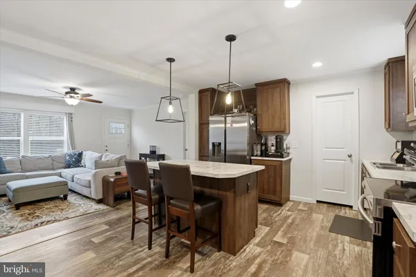 a view of a dining room and livingroom with furniture wooden floor a rug a fireplace and a chandelier