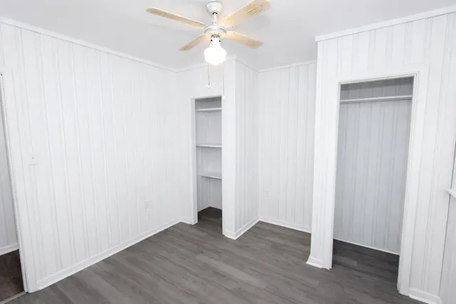 an empty room with wooden floor and a ceiling fan