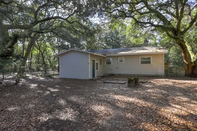 a backyard of a house with large trees and outdoor seating