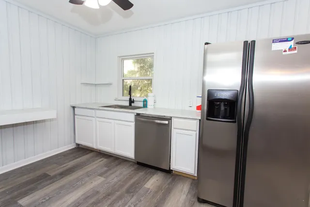 a kitchen with stainless steel appliances a refrigerator sink and wooden floor