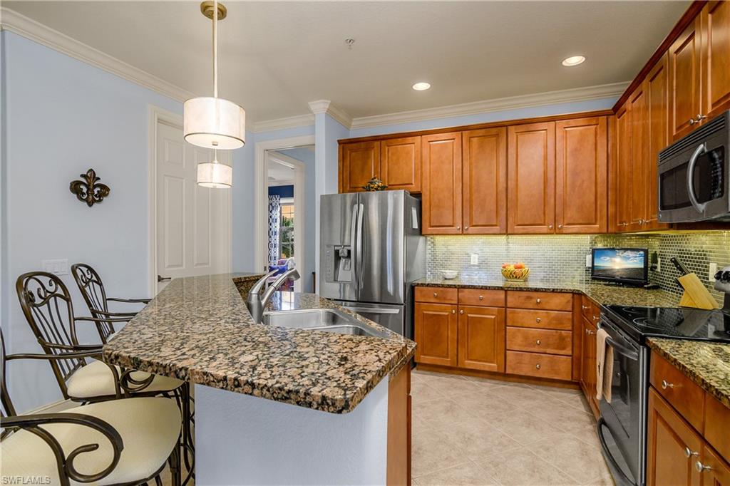 9108 Capistrano Street South, Unit 7402 Naples, FL 34113 - Photo 15 of 50 a kitchen with granite countertop cabinets a sink a window and stainless steel appliances