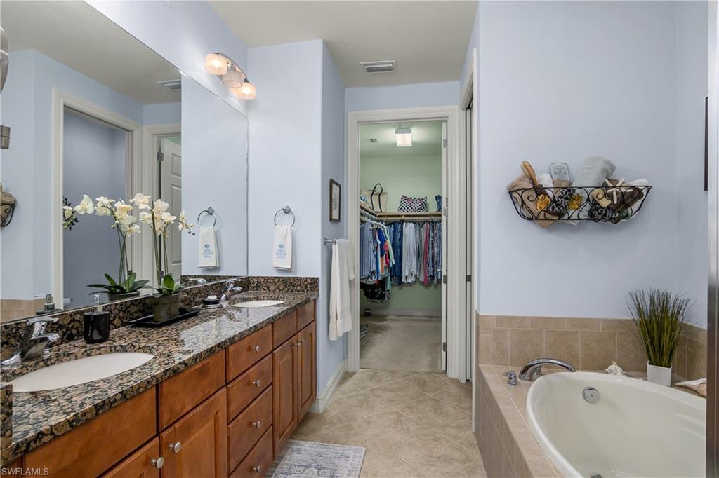9108 Capistrano Street South, Unit 7402 Naples, FL 34113 - Photo 23 of 50 a spacious bathroom with a granite countertop tub sink and mirror
