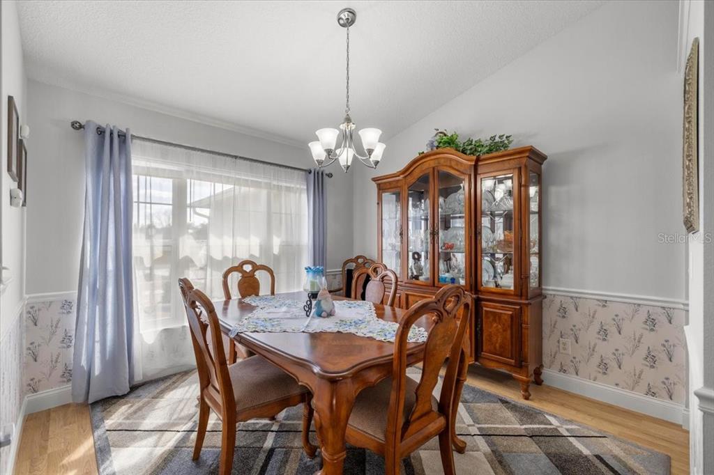 9957 Southwest 55th Ave Road Ocala, FL 34476 - Photo 7 of 41 a dining room with furniture a chandelier and wooden floor