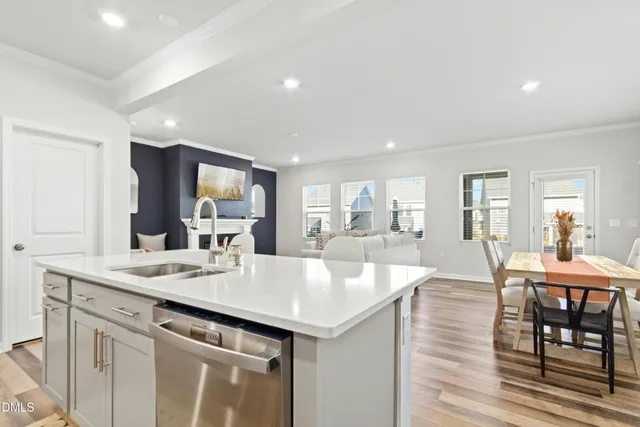 a kitchen with stainless steel appliances a sink a stove a microwave a dining table and chairs