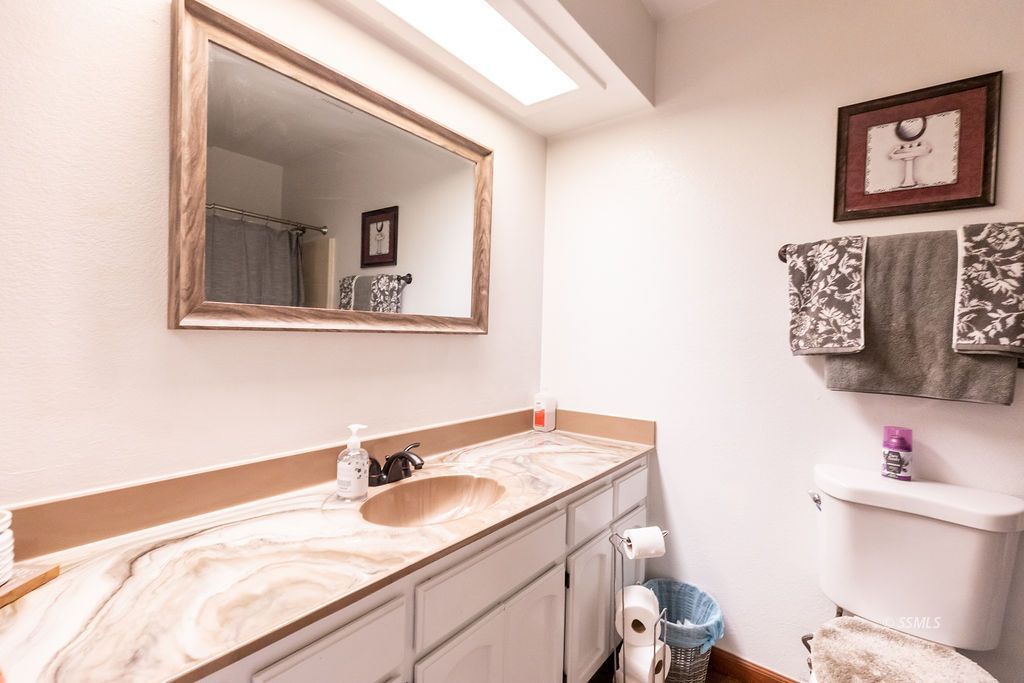 324 East Upjohn Avenue Ridgecrest, CA 93555 - Photo 19 of 35 a bathroom with a granite countertop sink and a toilet