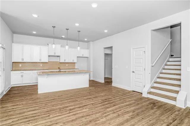 a large kitchen with kitchen island a sink wooden floor and a refrigerator