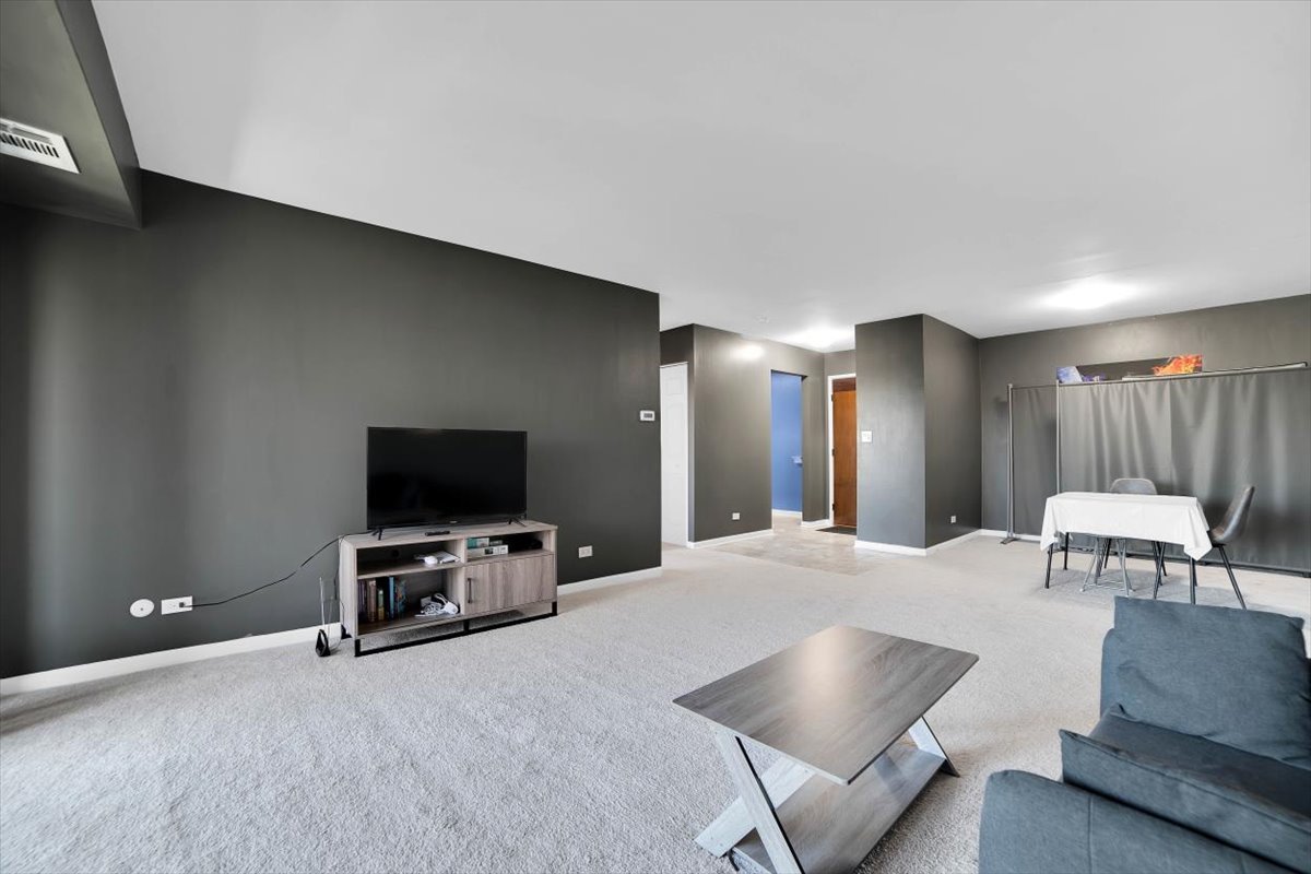 500 West Huntington Commons Road, Unit 448 Mount Prospect, IL 60056 - Photo 3 of 26 a living room with furniture and a flat screen tv