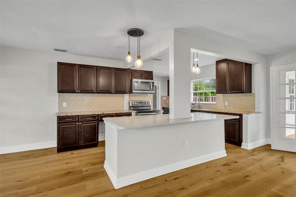 4234 Kendrick Road Orlando, FL 32804 - Photo 7 of 46 a kitchen with stainless steel appliances granite countertop a stove top oven a sink and a microwave