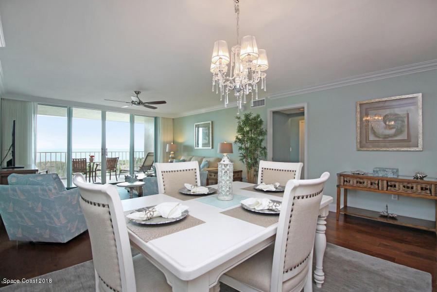 3400 Ocean Beach Boulevard, Unit 309 Cocoa Beach, FL 32931 - Photo 11 of 27 a view of a dining room with furniture a chandelier and wooden floor