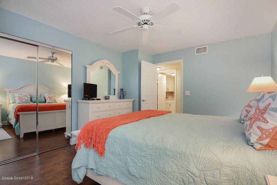 3400 Ocean Beach Boulevard, Unit 309 Cocoa Beach, FL 32931 - Photo 21 of 27 a bedroom with a large bed and a chandelier