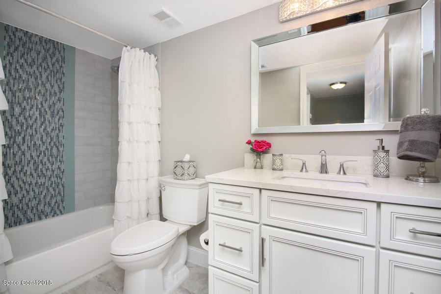 3400 Ocean Beach Boulevard, Unit 309 Cocoa Beach, FL 32931 - Photo 22 of 27 a bathroom with a granite countertop sink mirror vanity and toilet