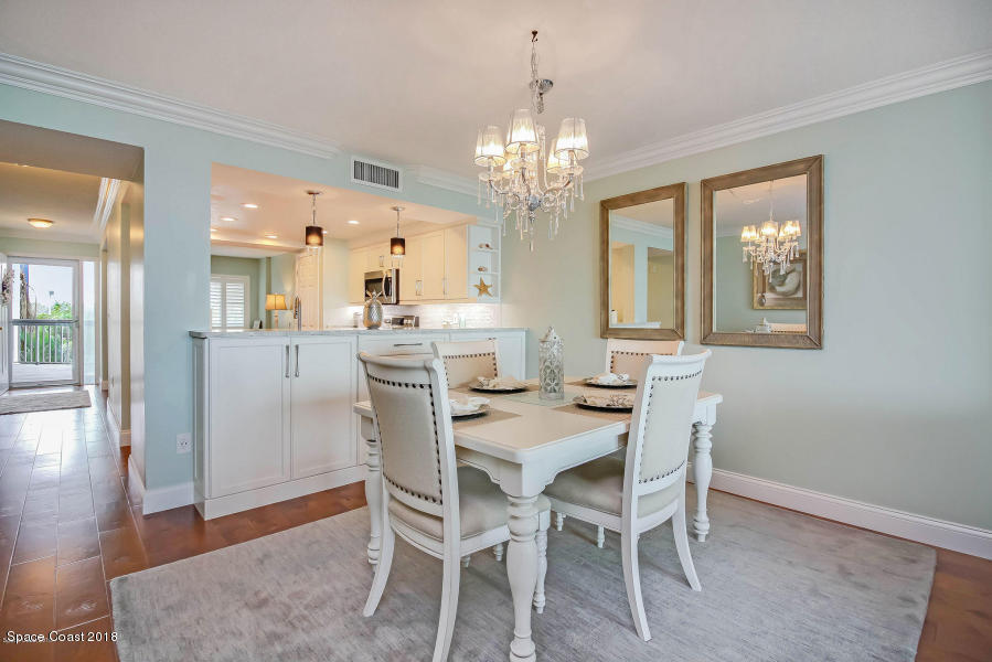 3400 Ocean Beach Boulevard, Unit 309 Cocoa Beach, FL 32931 - Photo 9 of 27 a view of a dining room with furniture a chandelier and wooden floor