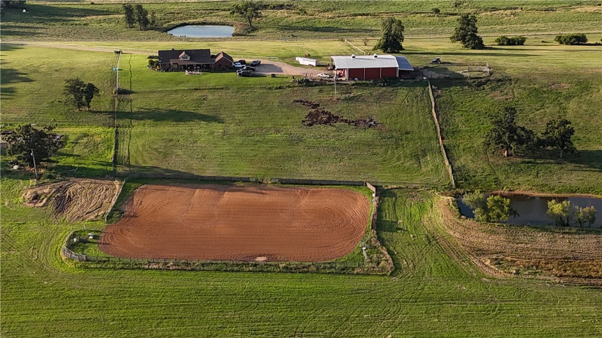 2210 Weiterer Road Scranton, AR 72863 - Photo 35 of 49 Expansive rural property featuring a large open field, a circular dirt arena, a main residence with a covered front porch, a separate red barn structure, and two distinct ponds