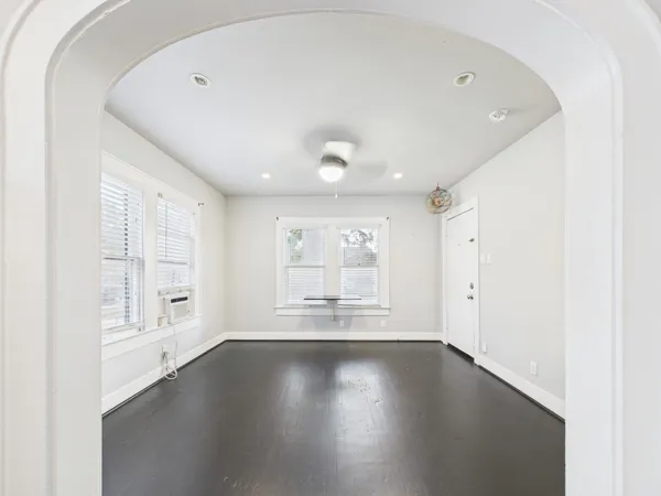 an empty room with wooden floor and windows with curtains