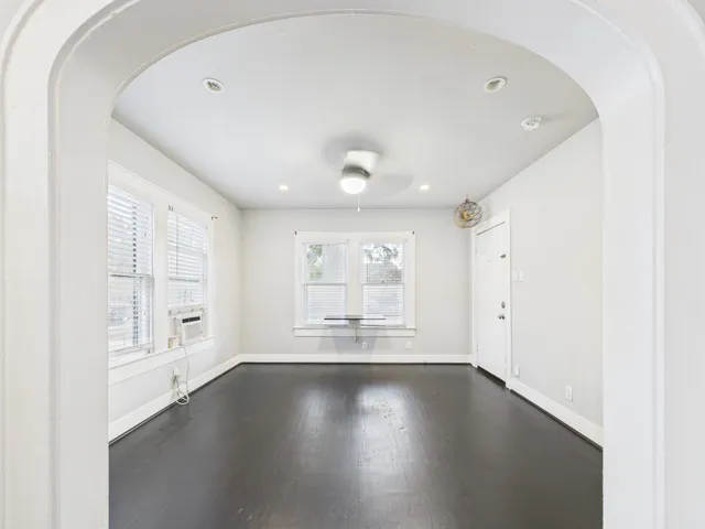 an empty room with wooden floor and windows with curtains