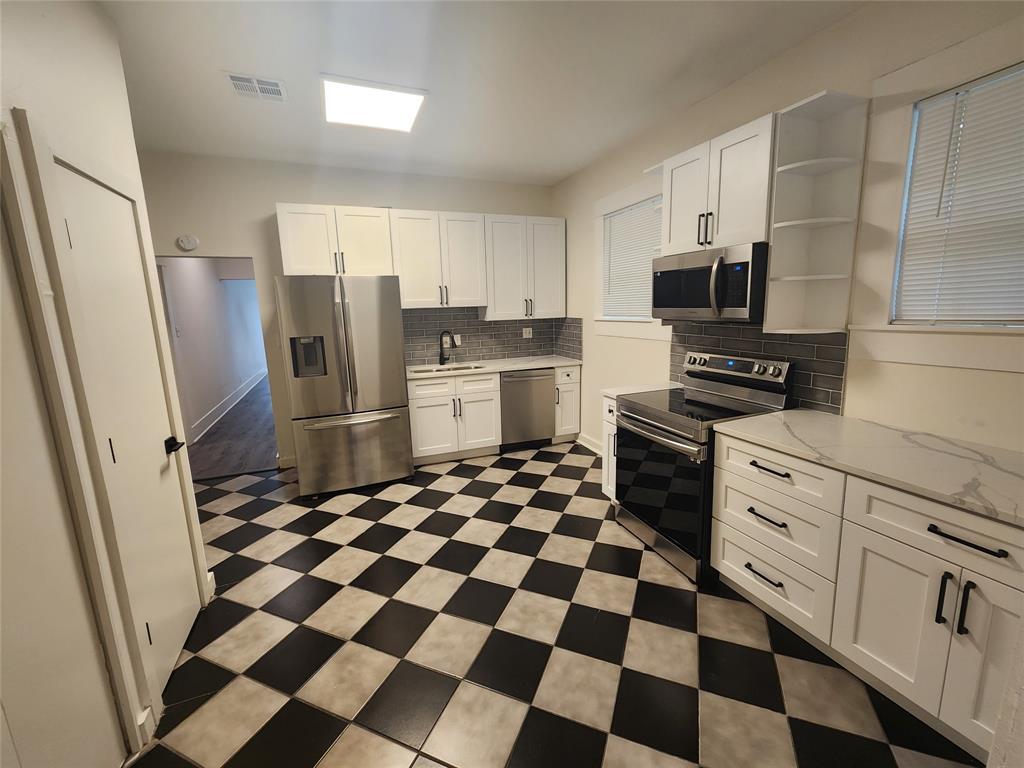 610 West 35th Street, Unit B Austin, TX 78705 - Photo 5 of 23 Kitchen featuring stainless steel appliances, white cabinets, open shelves, backsplash, and light stone countertops