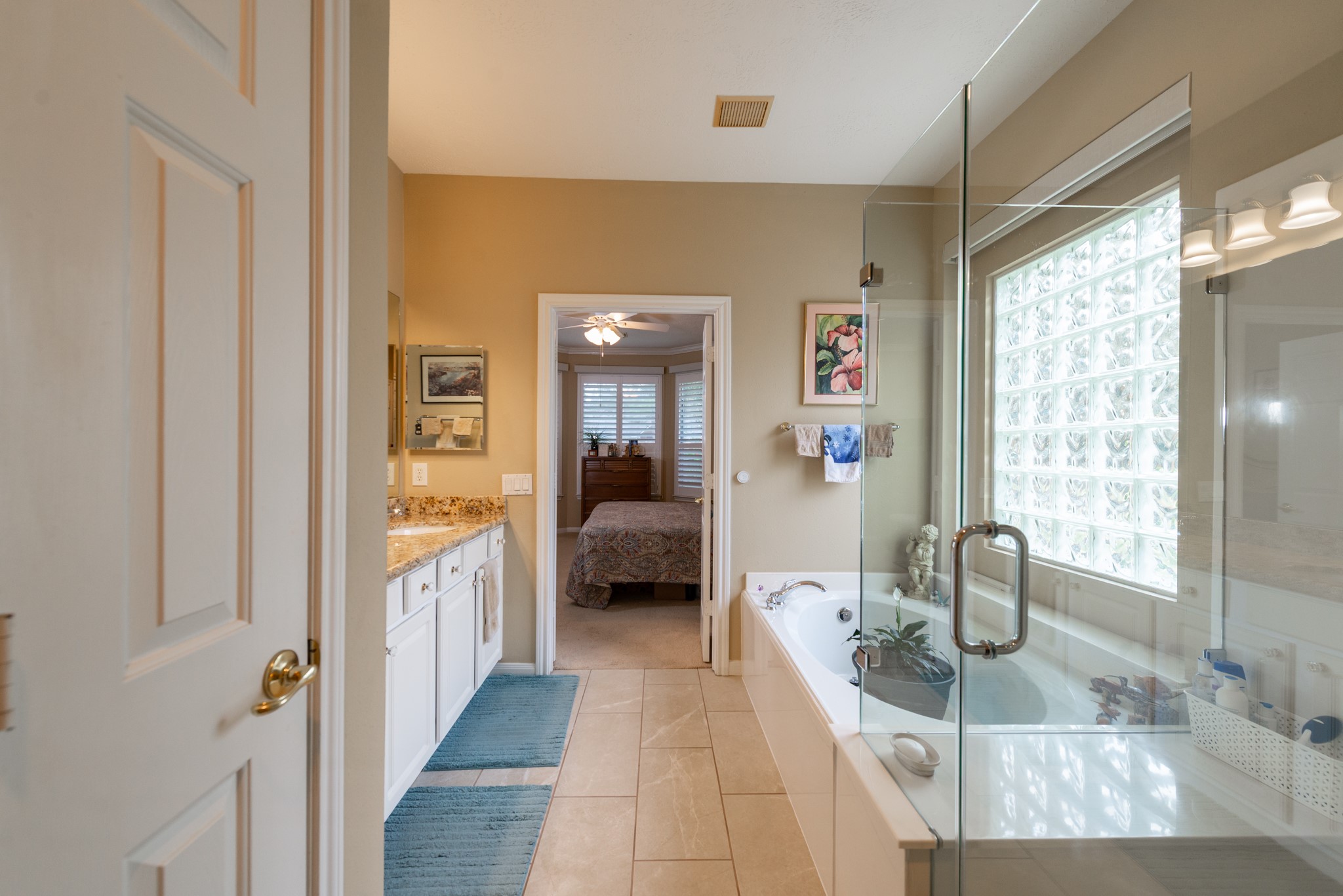 5230 Sandyfields Lane Katy, TX 77494 - Photo 18 of 24 Alternate view of the primary bathroom showing the glass-enclosed shower, soaking tub, and block glass window that provides natural light while maintaining privacy.