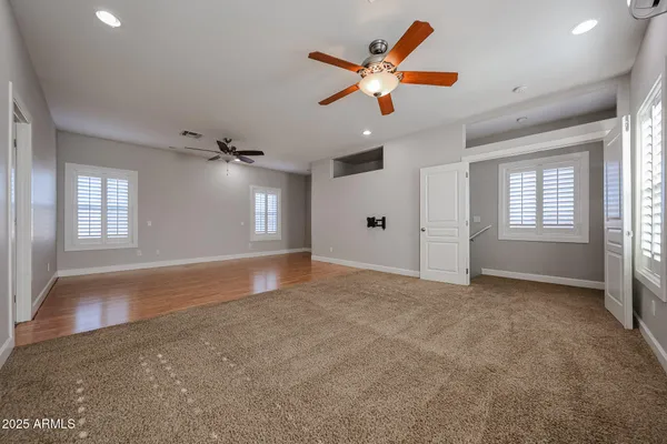 an empty room with windows and fan