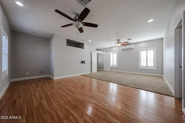 a view of empty room with wooden floor and fan