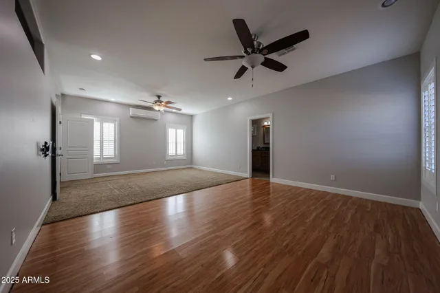 a view of empty room with wooden floor and ceiling fan
