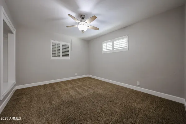 en empty room with windows and chandelier fan