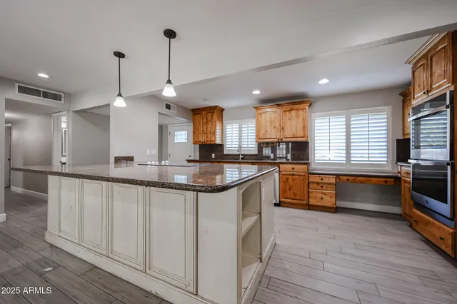 a kitchen with stainless steel appliances granite countertop a sink a stove a refrigerator and island with wooden floor