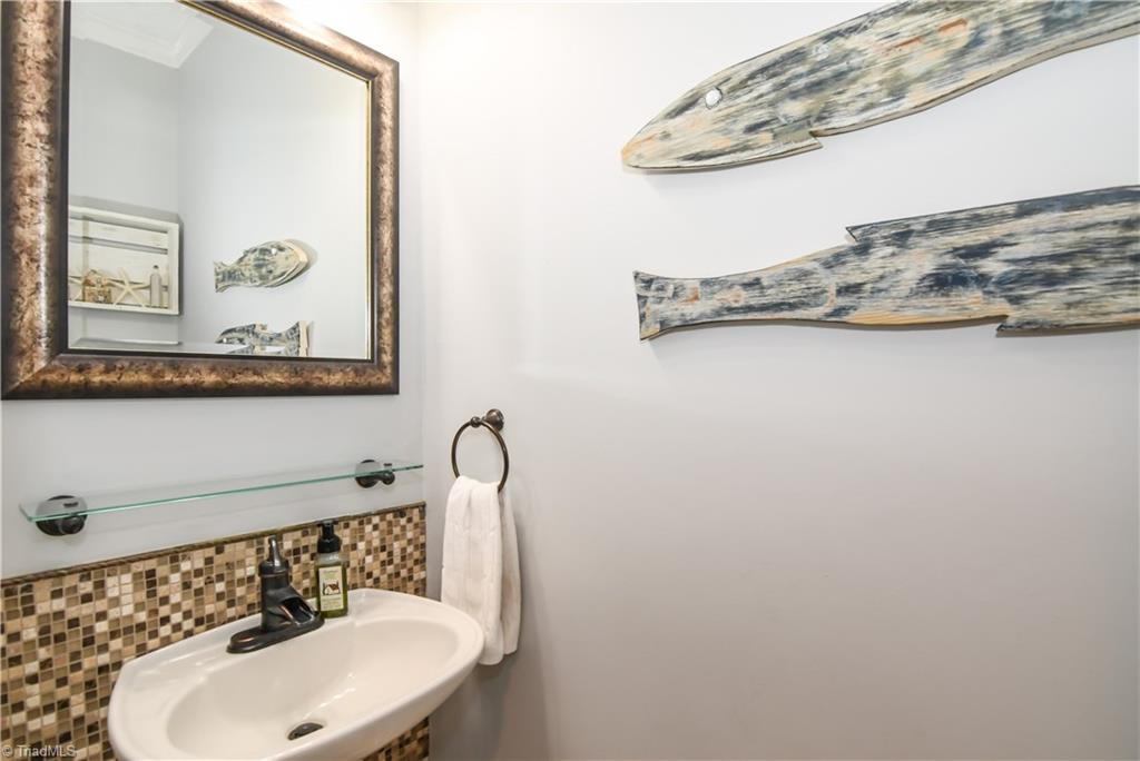 6401 High View Road Greensboro, NC 27410 - Photo 12 of 28 Downstairs half bath features tile floors, a pedestal sink, updated lighting & fixtures and a tile back splash!