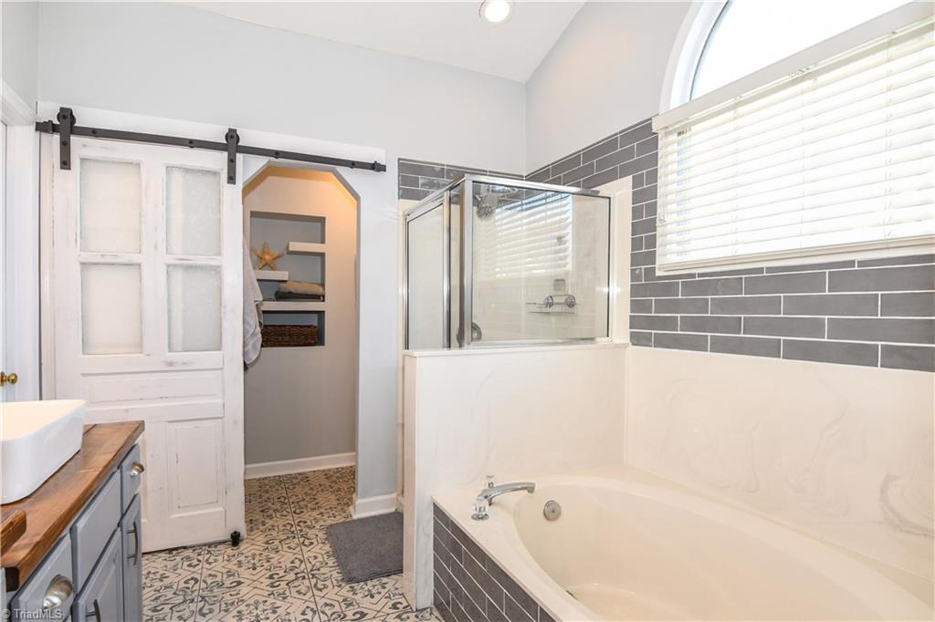 6401 High View Road Greensboro, NC 27410 - Photo 16 of 28 A separate shower and garden tub both surrounded by subway tile, large window allows lots of natural light, vaulted ceiling and a beautiful barn door that closes to separate the water closet which features bead board on the ceiling & built in shelves!