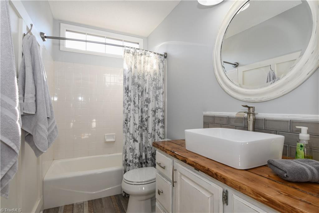 6401 High View Road Greensboro, NC 27410 - Photo 19 of 28 Upstairs guest bathroom features tile flooring, shower/tub combo, updated vanity with subway tile back splash, new mirror and lighting!