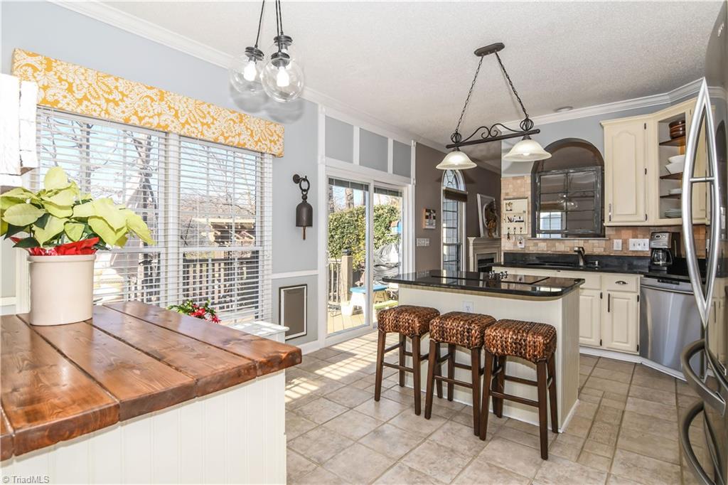 6401 High View Road Greensboro, NC 27410 - Photo 7 of 28 This fantastic kitchen features tile flooring, updated light fixtures, a butcher block work space and an island with a cook top, granite & bar seating!