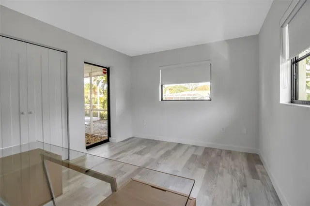 a view of an empty room with a window and a kitchen