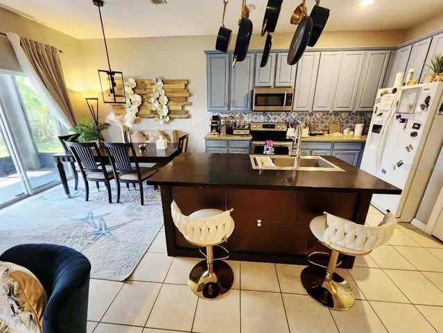 a kitchen with stainless steel appliances kitchen island granite countertop a sink a stove a dining table and chairs