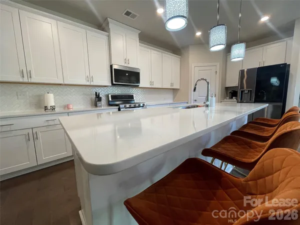 a kitchen with stainless steel appliances granite countertop a sink a stove top oven a counter space and cabinets
