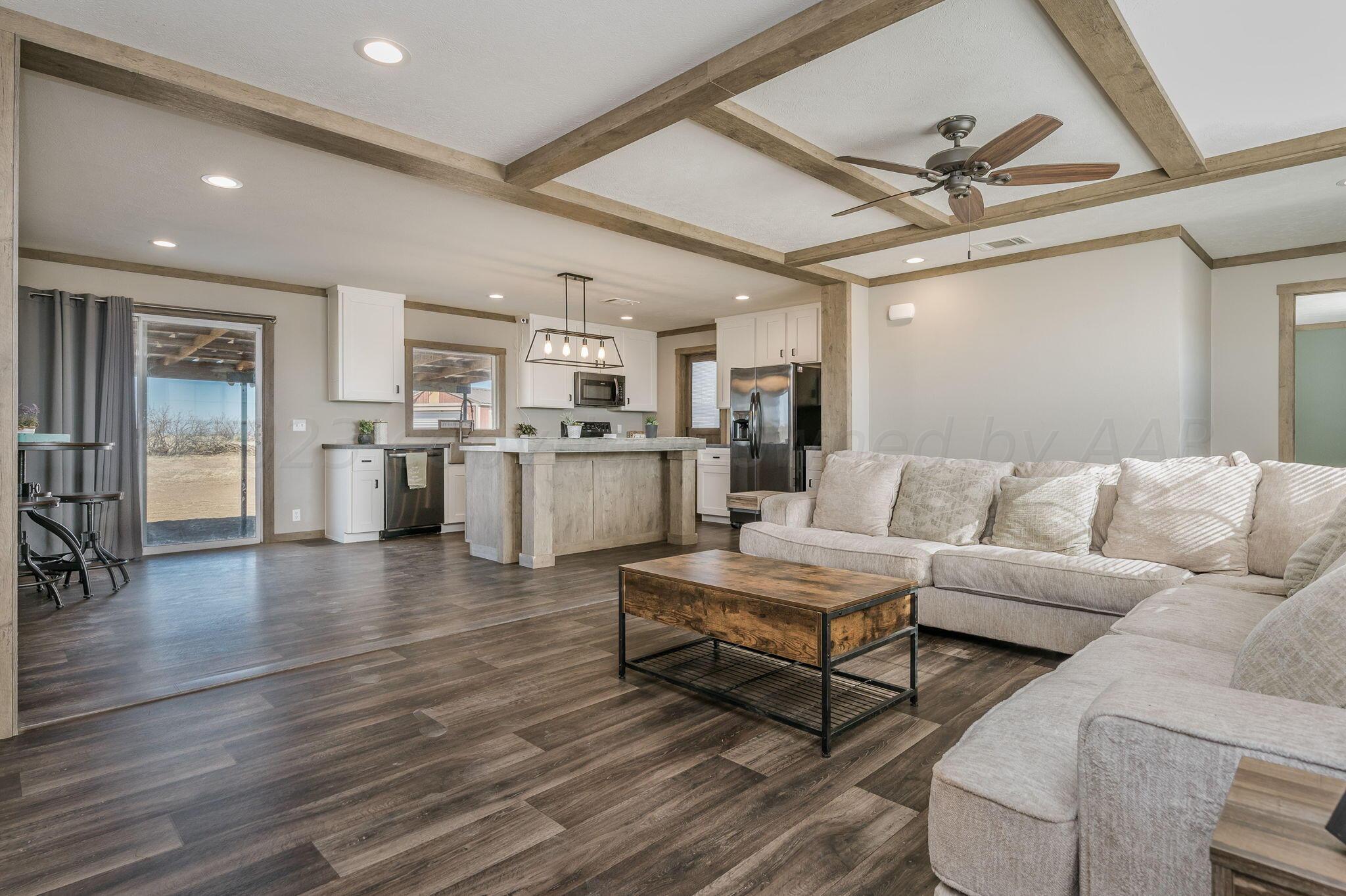 a living room with stainless steel appliances furniture and a kitchen view