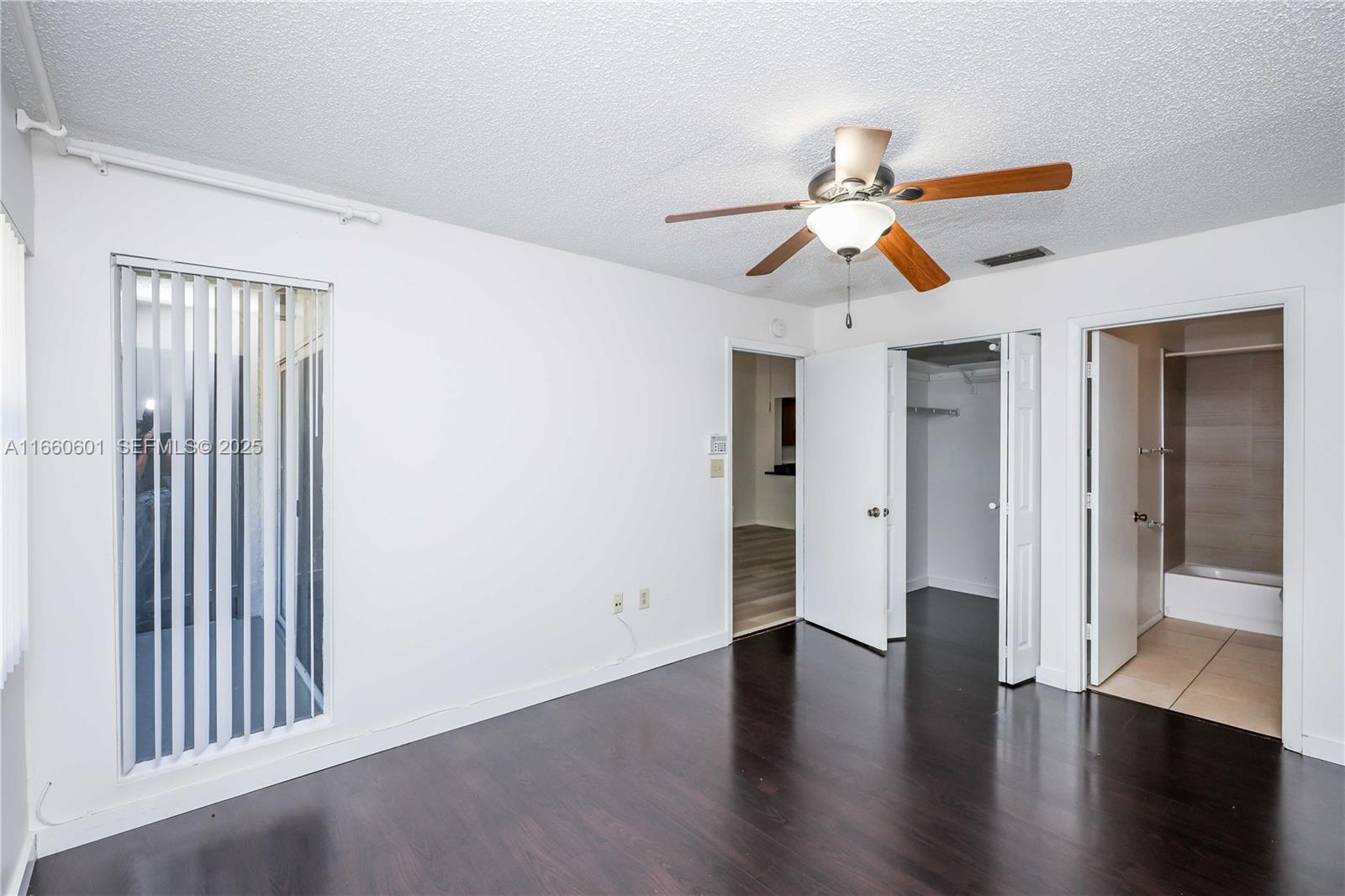 446 Southwest 113th Way, Unit 446 Pembroke Pines, FL 33025 - Photo 12 of 39 an empty room with wooden floor chandelier fan and windows