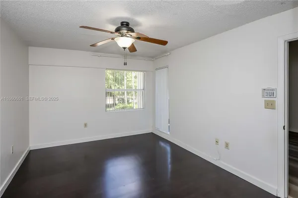 an empty room with wooden floor chandelier fan and windows